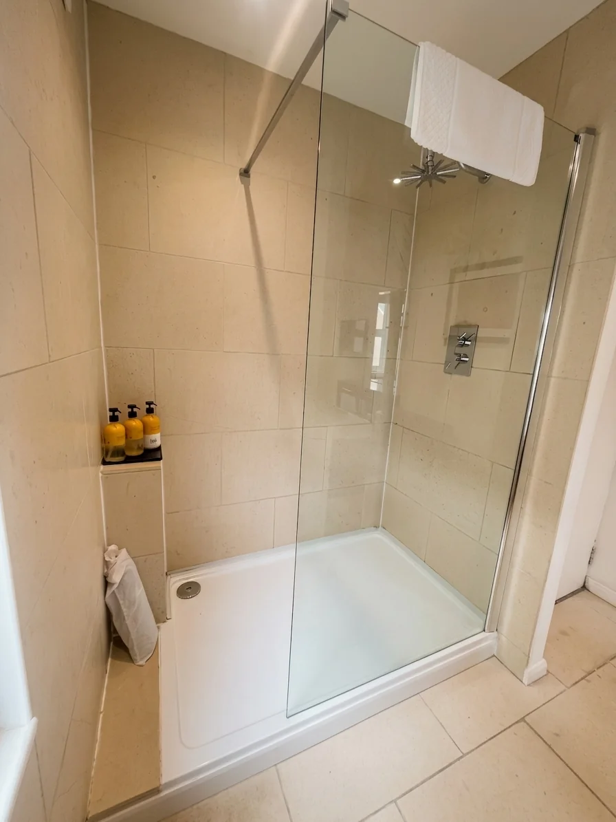 Hastings House Bedroom 1 ensuite — walk-in shower with limestone tiles and Wild England products