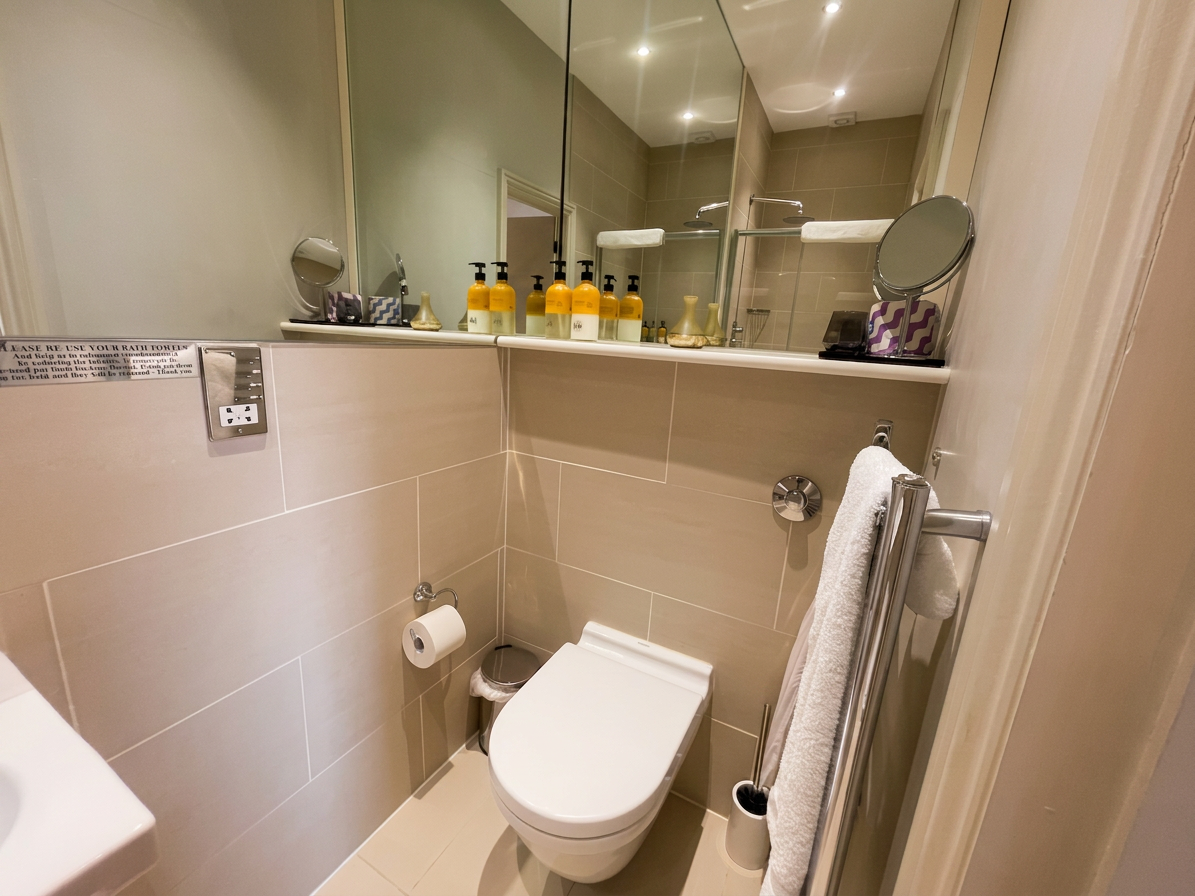 Hastings House Bedroom 4 ensuite — taupe tiles, mirrored cabinet and chrome fittings with Wild England toiletries