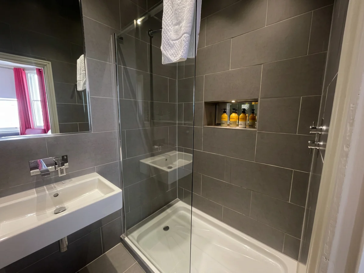 Hastings House Bedroom 7 ensuite — dark grey tiled shower with Wild England toiletries