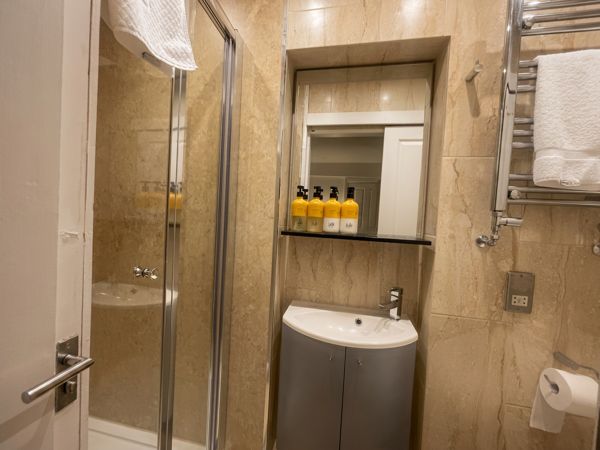 Hastings House Bedroom 9 ensuite — marble-effect tiles, corner basin unit and chrome shower
