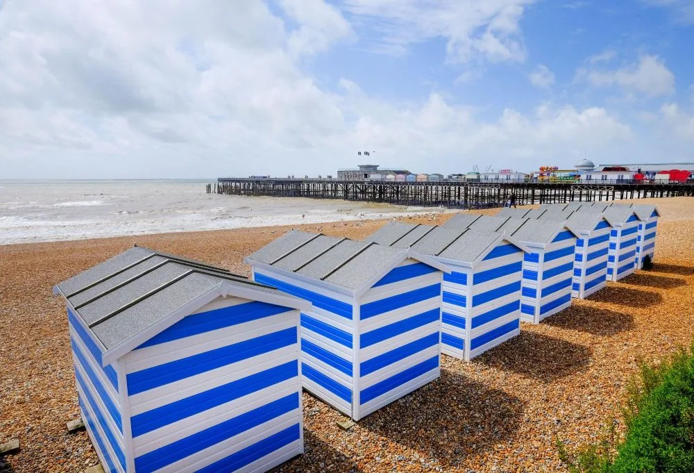 Colourful blue and white beach huts on Hastings seafront with the pier in the background