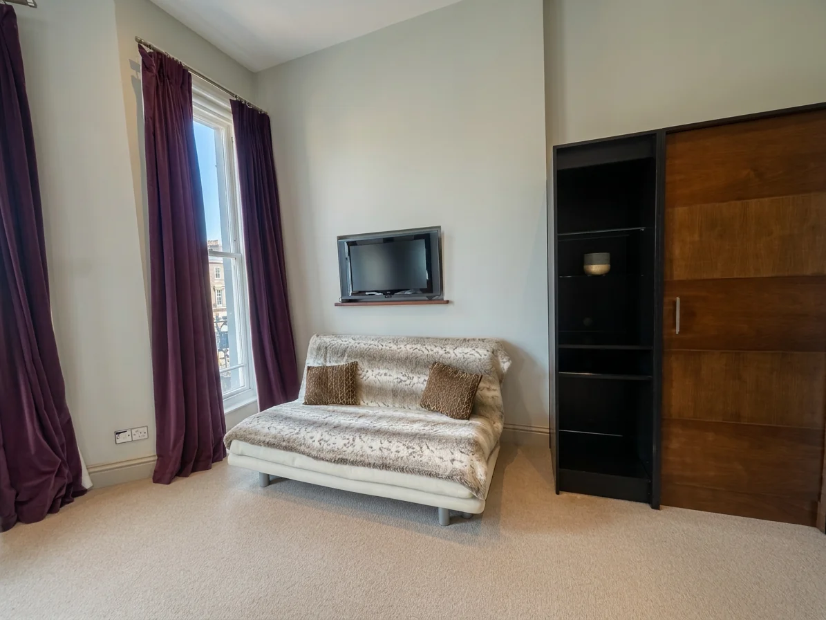Hastings House Bedroom 3 — sofa area with TV and walnut wardrobe