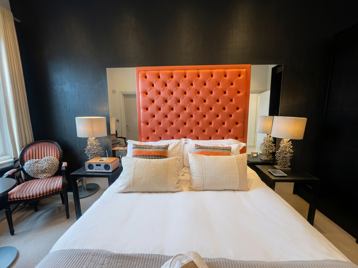 Hastings House Bedroom 6 — orange headboard with coral lamps and striped armchair