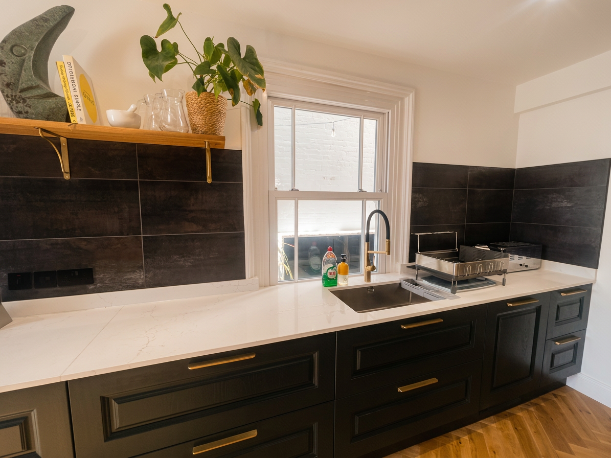 Hastings House kitchen — dark cabinetry, marble worktop and brass sink tap