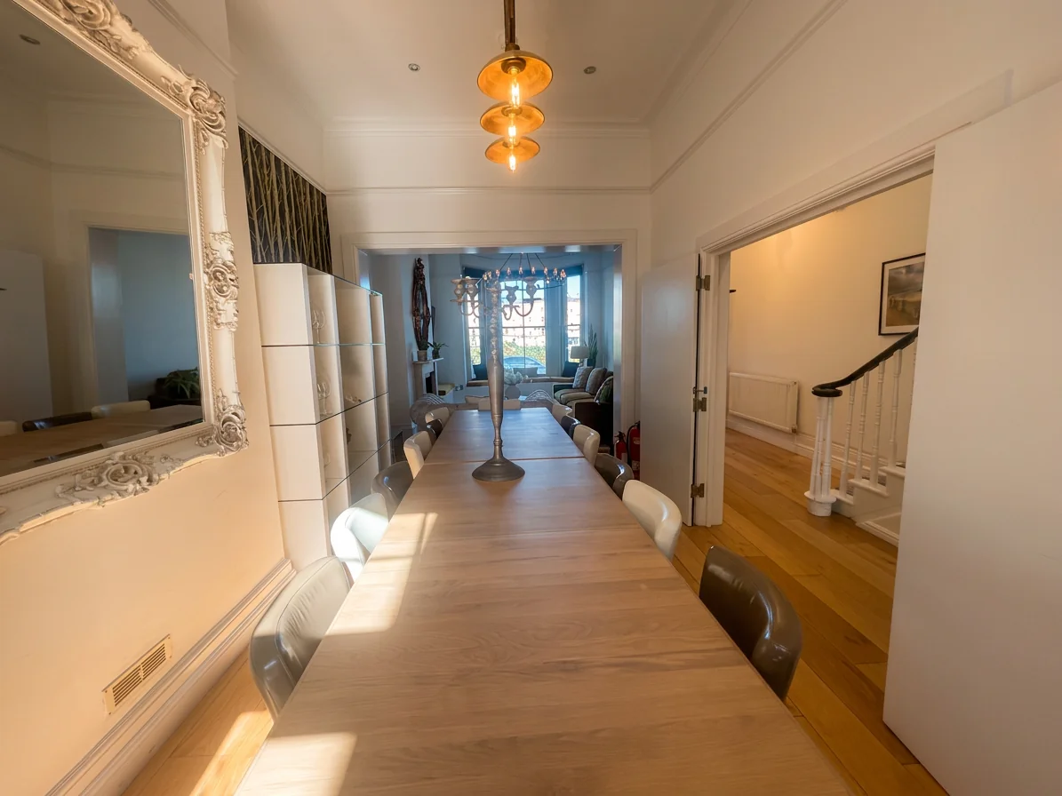Hastings House long dining table with pendant light, white ornate mirror and view through to lounge