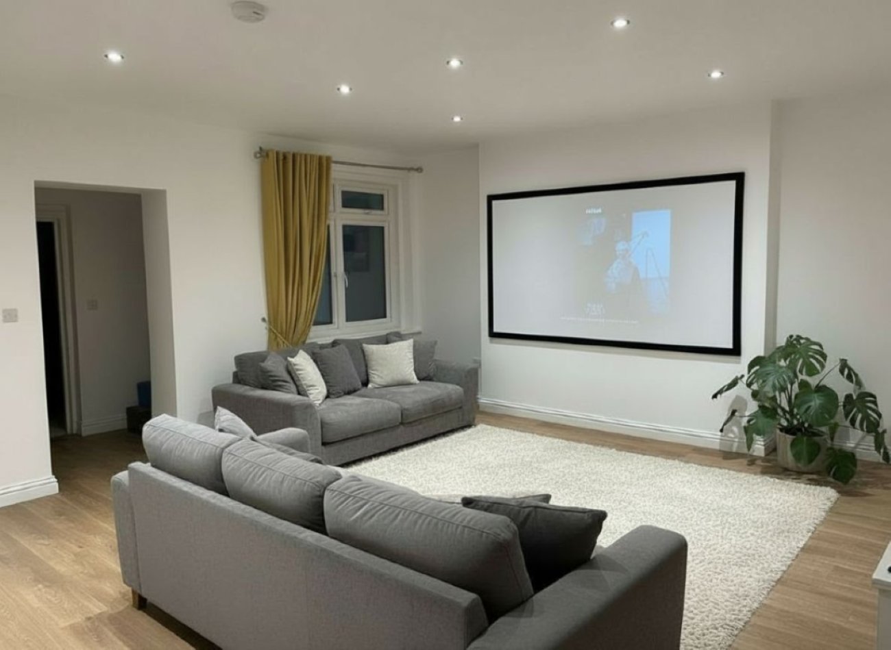 Hastings House cinema lounge with projector screen and grey sofas
