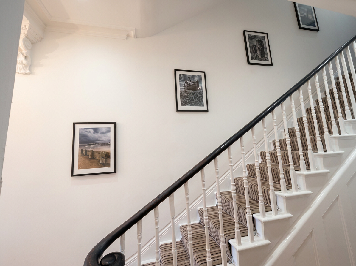Hastings House staircase with striped runner and Hastings artwork gallery wall